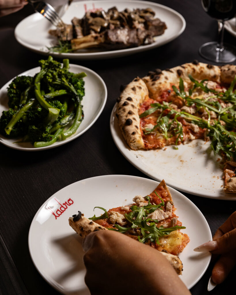 Pizza, broccoli, and meat dish on a table.