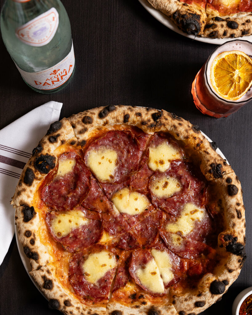 Salami pizza with drinks on a table
