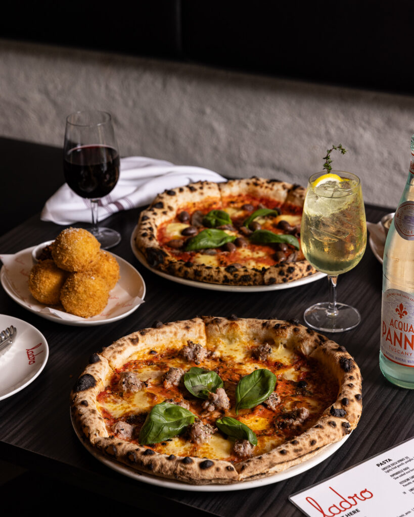 Gourmet pizzas and drinks on a restaurant table.