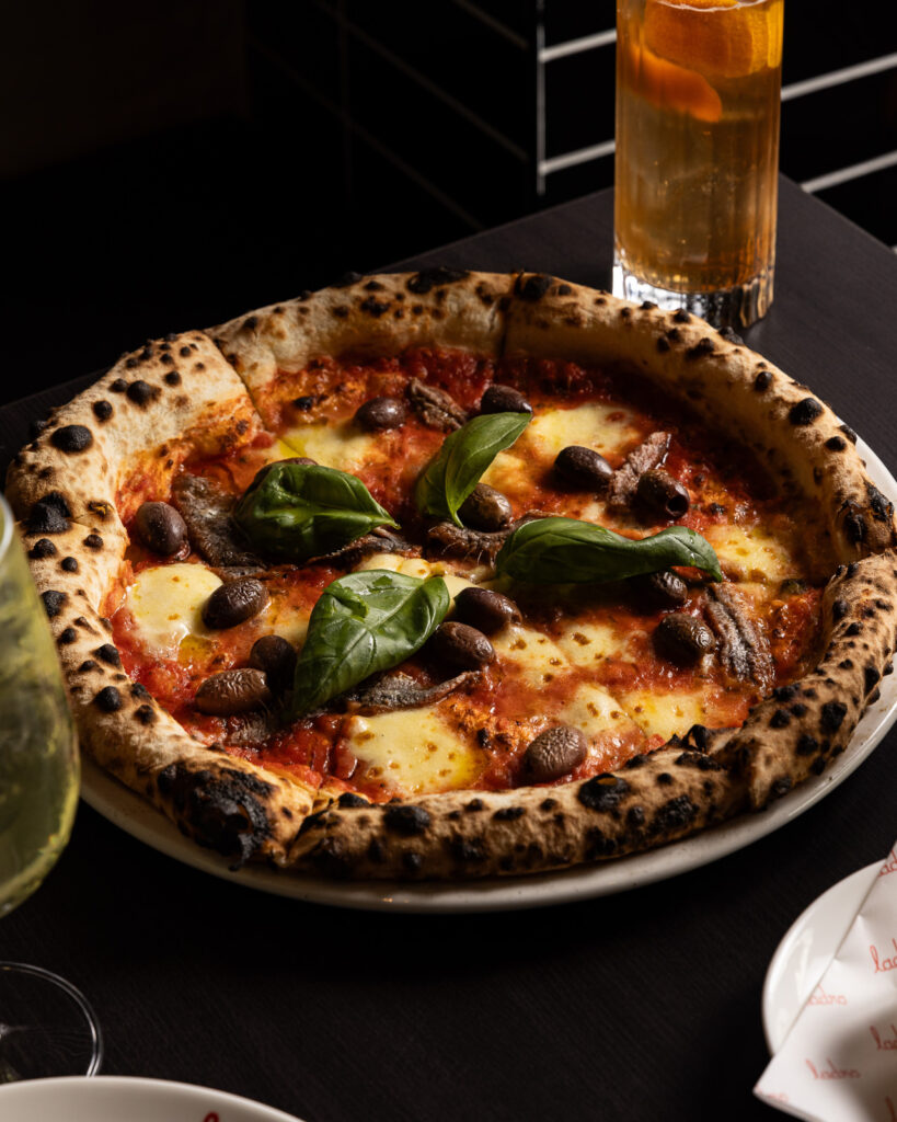 Gourmet pizza with olives, anchovies, and basil.