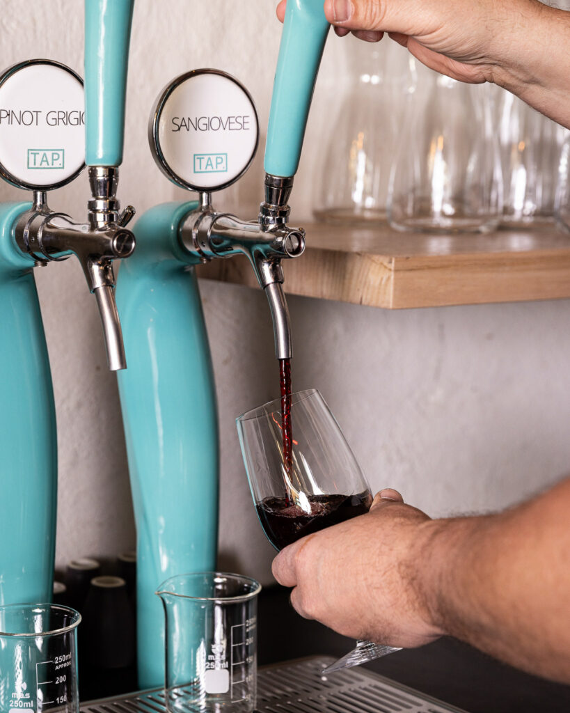 Pouring Sangiovese wine from tap into glass.