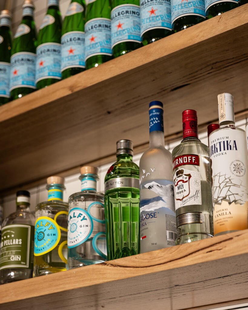 Bottles of various gins and vodkas on shelves.