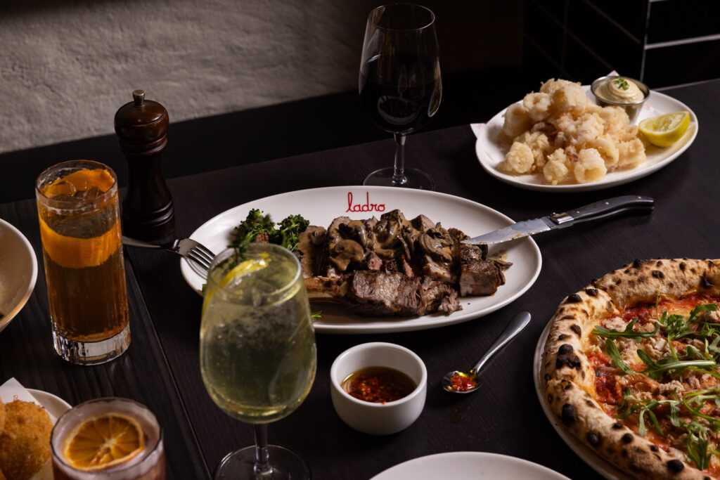 A serve of rib eye tagliata on a table surrounded by sides.