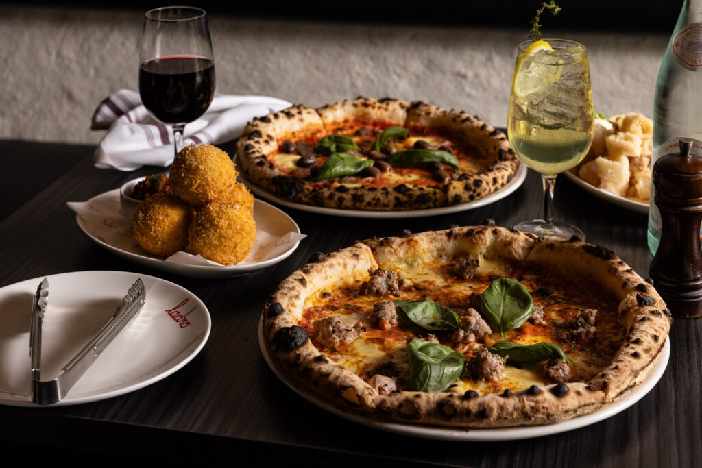 Gourmet pizzas with drinks on a dining table.