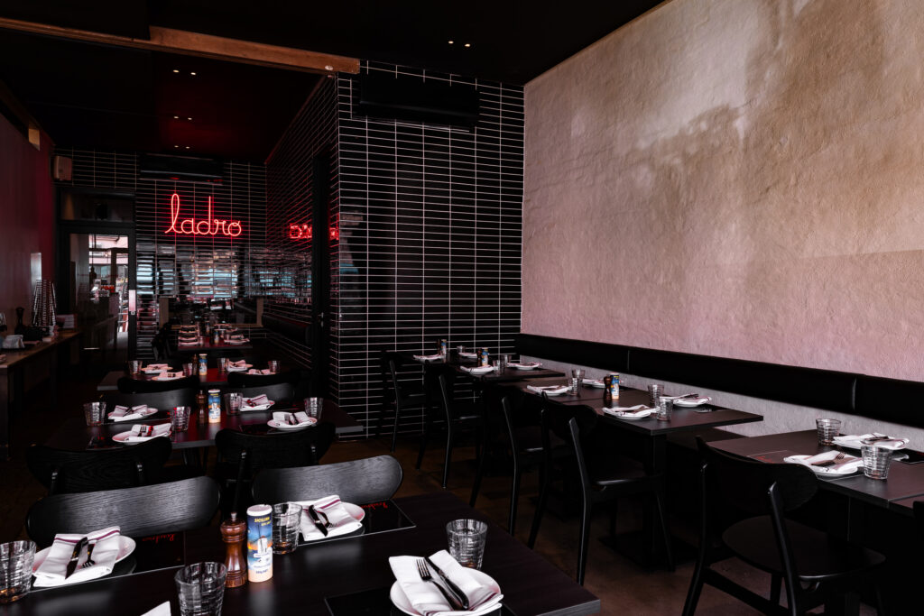 Modern restaurant interior with neon sign and set tables.