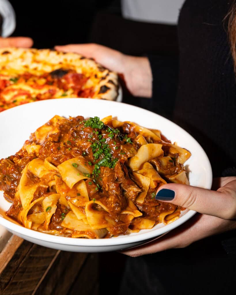 Pasta and pizza dishes being served.