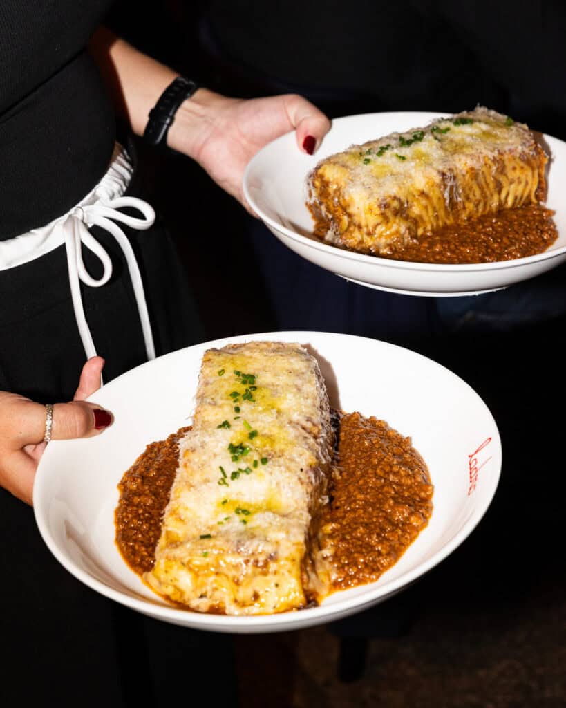 Lasagna with bolognese sauce served on white plates.