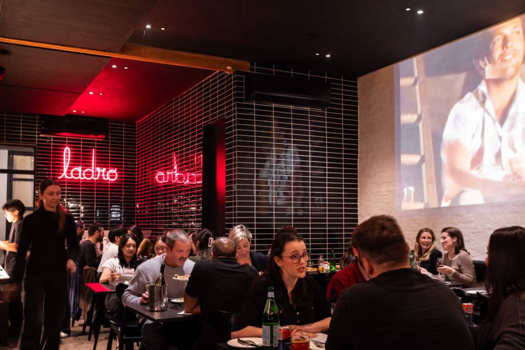 Busy restaurant with neon lights and projected image.