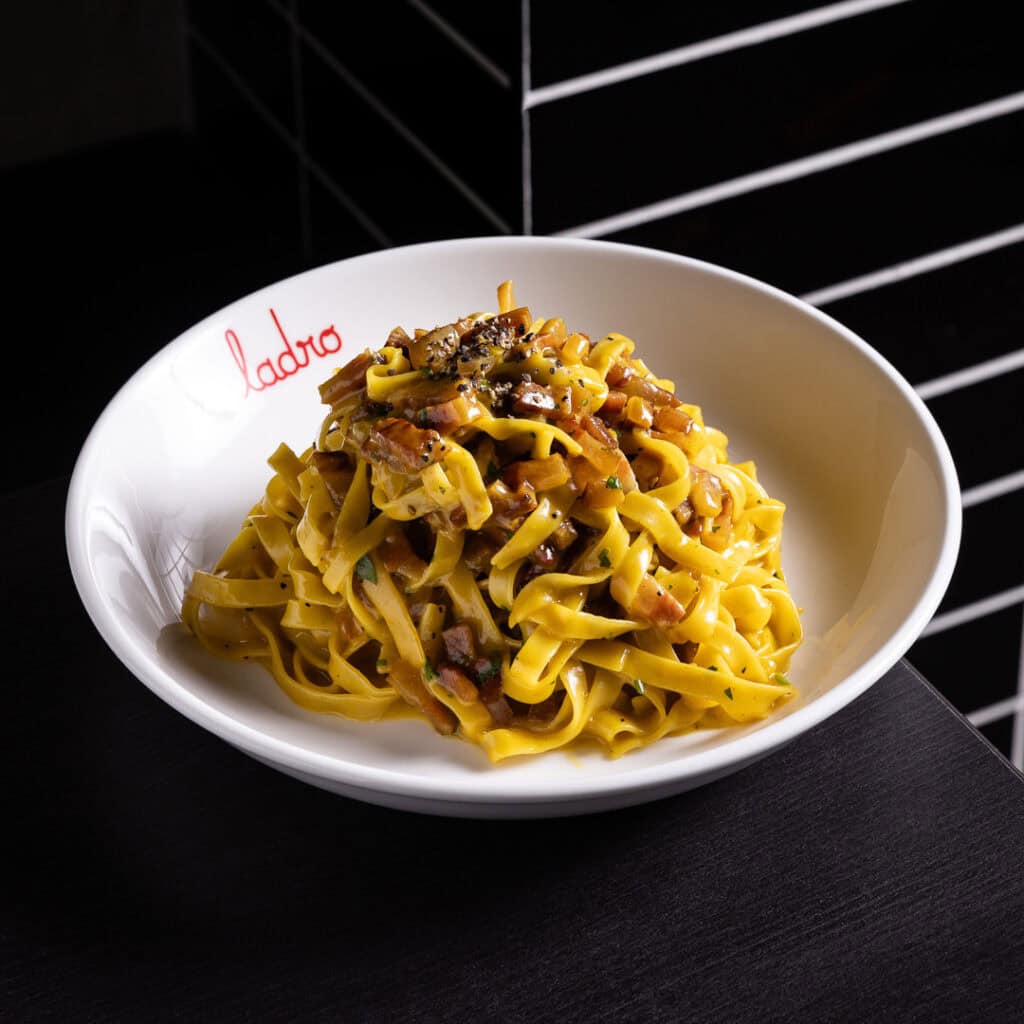 Tagliatelle pasta with sauce in a white bowl.