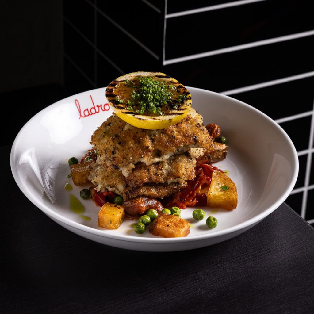 Gourmet chicken dish with vegetables and grilled lemon.