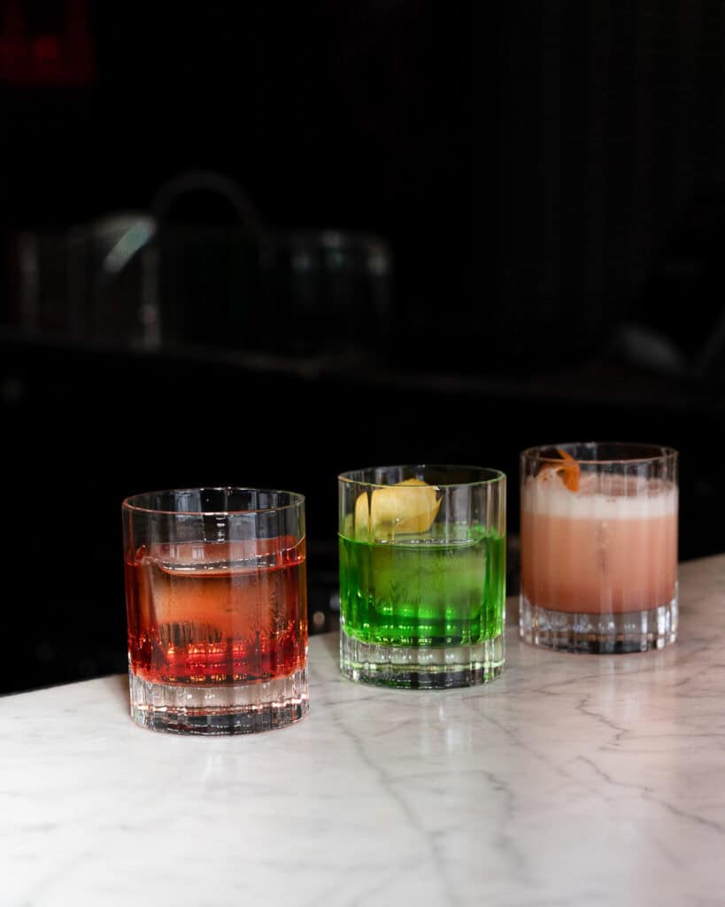 Three colorful cocktails on marble countertop.
