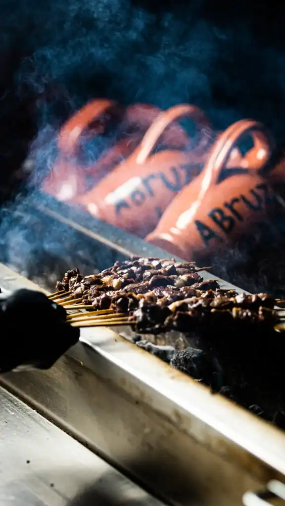 Skewered grilled meat cooking over charcoal fire.
