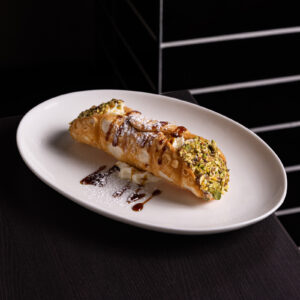 Italian cannoli with pistachio on white plate